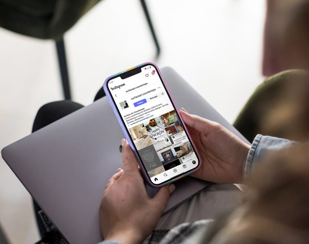 Woman holding a phone and looking a the Social Media managment for small business Surface Art Counertops by KS Marketing
